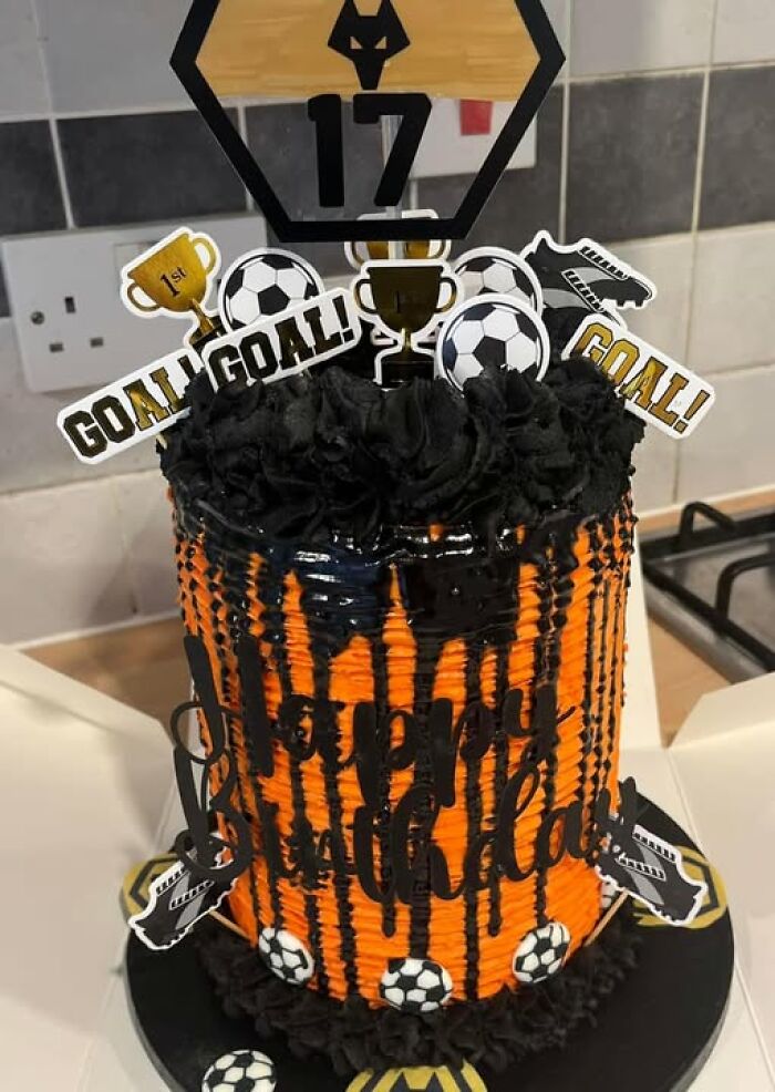 Soccer-themed birthday cake with black icing drips and soccer ball decorations.