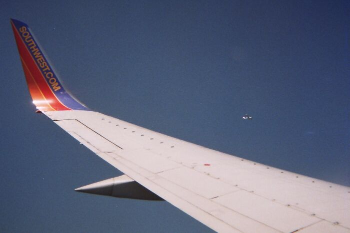 Airplane wing in flight with a distant jet, capturing an incredible moment for proof.