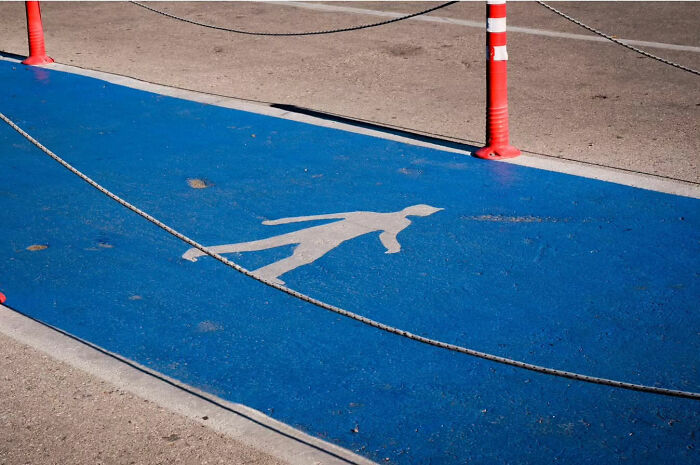 Street life captured in a blue pedestrian path with ropes and a silhouette, highlighting urban beauty.