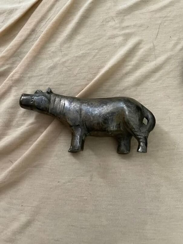 Metallic hippo figurine found while thrifting, placed on a beige fabric surface.