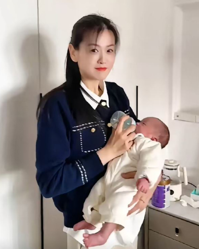 A young-looking grandmother feeding a baby with a bottle, showcasing youthful appearance and family bonding. A young-looking grandmother feeding a baby with a bottle, showcasing youthful appearance and family bonding.