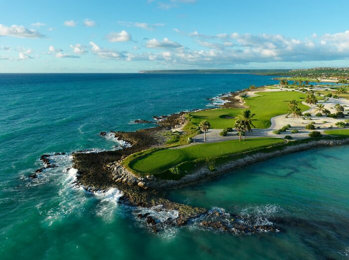 Breathtaking golf course by the ocean, surrounded by lush greenery and clear blue waters.