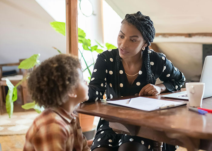 Mom uses gentle parenting technique in conversation with child at a wooden table, emphasizing empathy and understanding. Mom uses gentle parenting technique in conversation with child at a wooden table, emphasizing empathy and understanding.