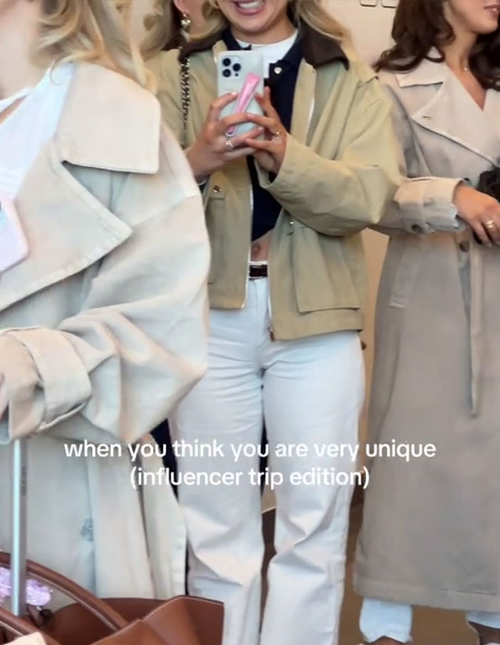 Influencers in similar beige trench coats at an event, reflecting a uniform fashion trend.