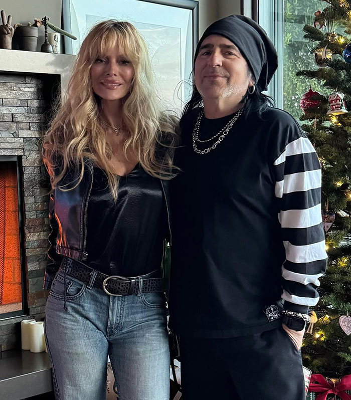 Couple posing indoors, standing near a decorated Christmas tree.