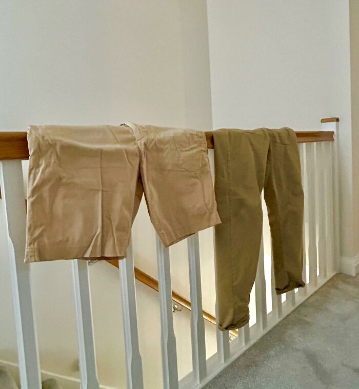 Trousers drying on a stair railing inside a British home, capturing a quirky British domestic moment.