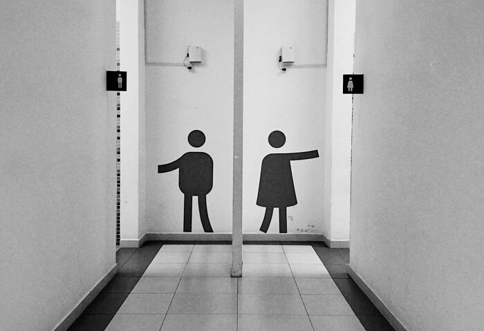 Humorous restroom signs with pointing figures, reminiscent of the worst job interviews in history.