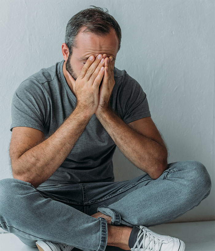 Man in distress sitting, planning surprise for daughter with tapes of her late mother, looking troubled.