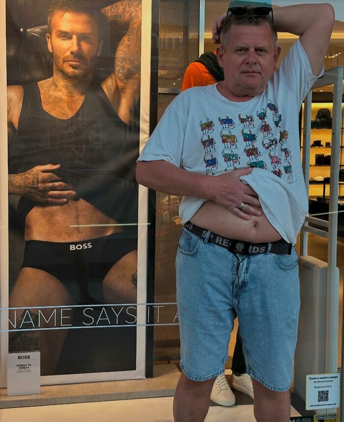 Man mimicking model pose in front of an ad, creating a perfectly timed street photo moment.