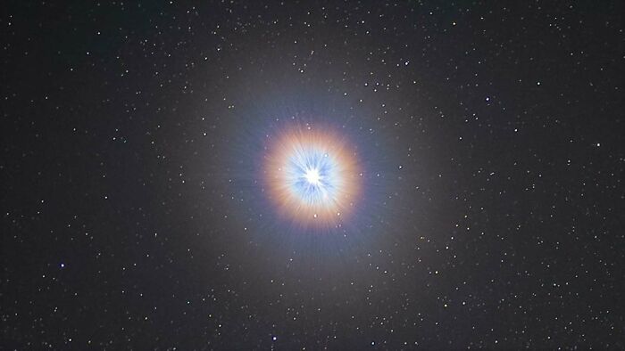 Astrophotography image of a bright starburst with colorful halo against a starry night sky background.