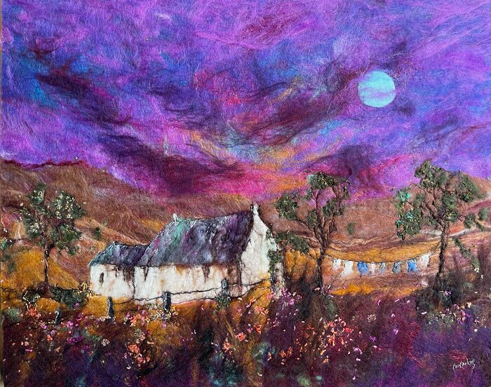 Fiber art scenery by Moy Mackay featuring a cottage under a vivid purple sky and glowing moon.