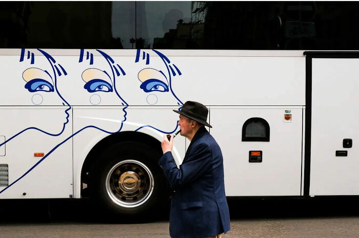 Elderly man in hat walking by bus with artistic face designs, capturing street life's raw beauty.