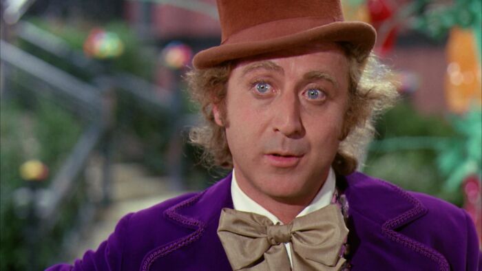 Actor in iconic role, wearing a brown hat and purple coat, embodying a character as if born for it.