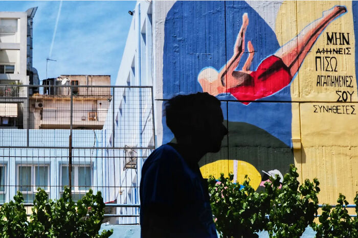 Silhouette of a person walking past a colorful mural, capturing the raw beauty of street life.