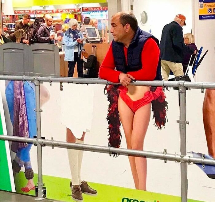 Man leaning on a rail, perfectly timed with a humorous poster showing unexpected moments.