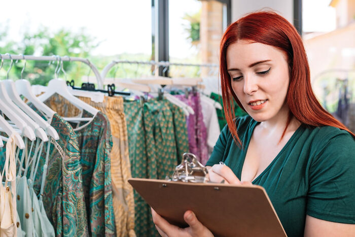 Woman with clipboard checking clothes, illustrating life after a "useless" degree.