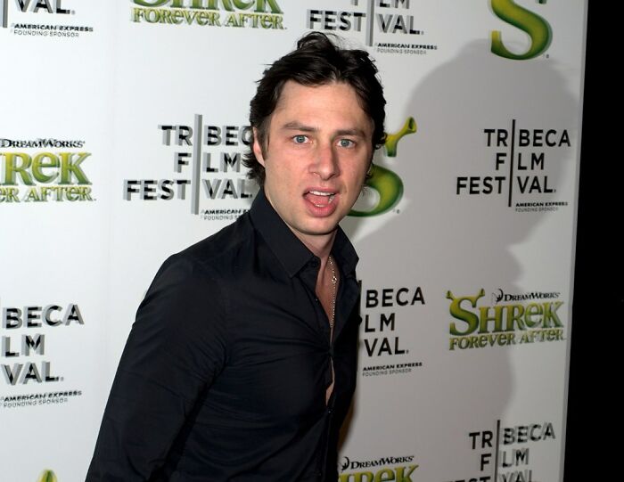 Man in a black shirt making a funny face at a film festival event backdrop.