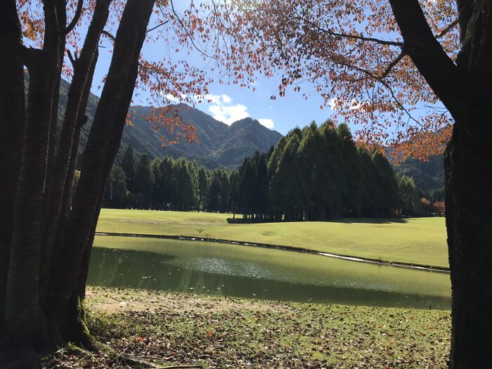 Breathtaking golf course with lush greens, serene pond, and mountain backdrop.