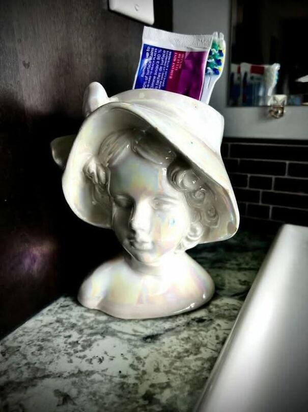 Bust vase used as a toothbrush holder found while thrifting, placed on a bathroom counter.