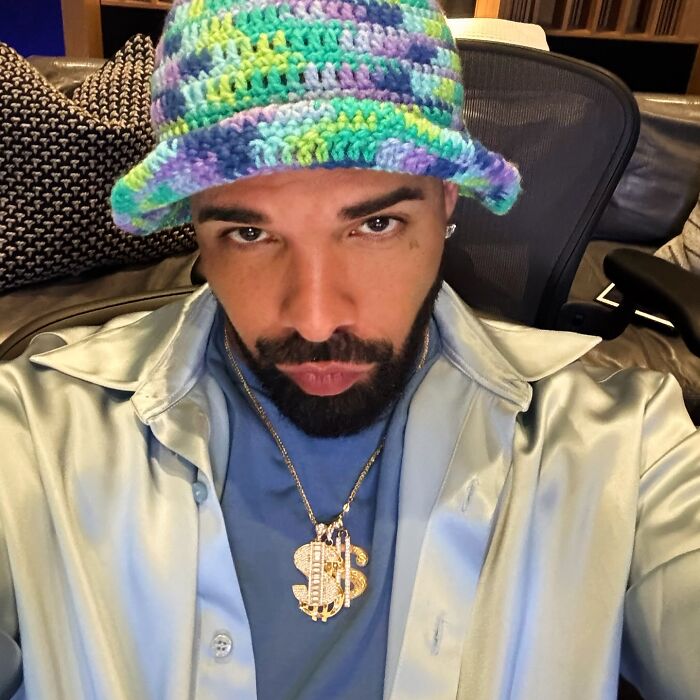 Celebrity in a colorful crochet hat and shiny shirt, symbolizing extravagant lifestyle choices.