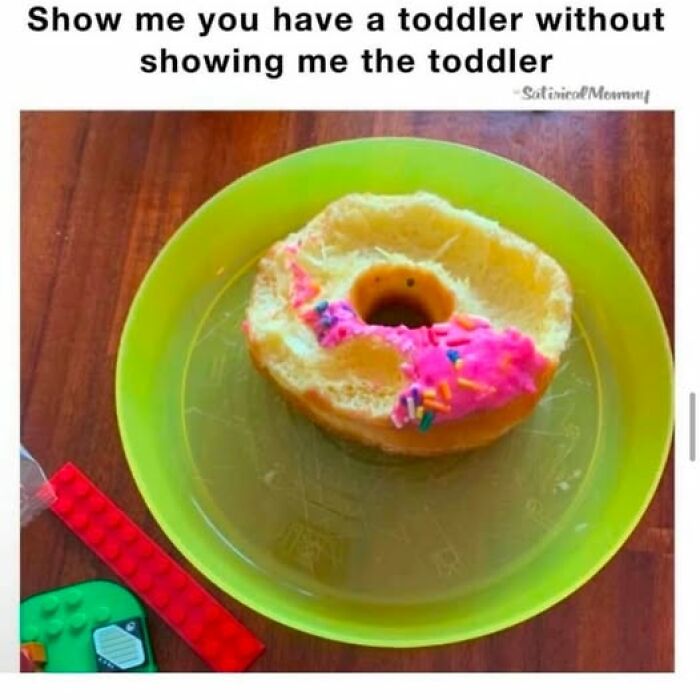 Donut with missing icing on a green plate, surrounded by toddler toys; a perfect parenting meme moment.
