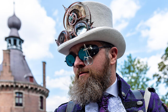 Man with steampunk attire and glasses in front of historical building, representing graduates with "useless" degrees.