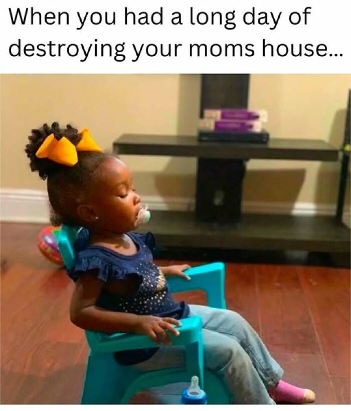 A toddler with a pacifier and bow, looking tired in a blue chair; a funny parenting meme.