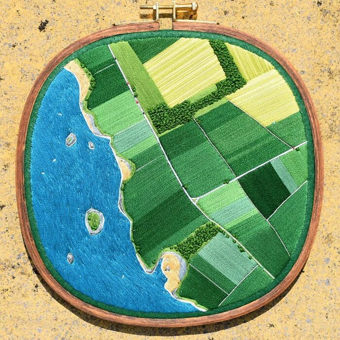 Landscape embroidery depicting fields and a coastline in vibrant colors.