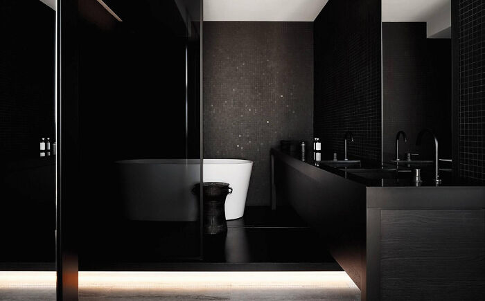 Minimalist black bathroom with freestanding bathtub and double sink, showcasing interior design trends to avoid aging poorly.