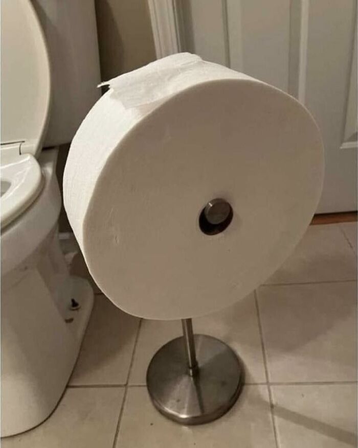 Giant toilet paper roll on stand in bathroom, creating a funny and random scene.