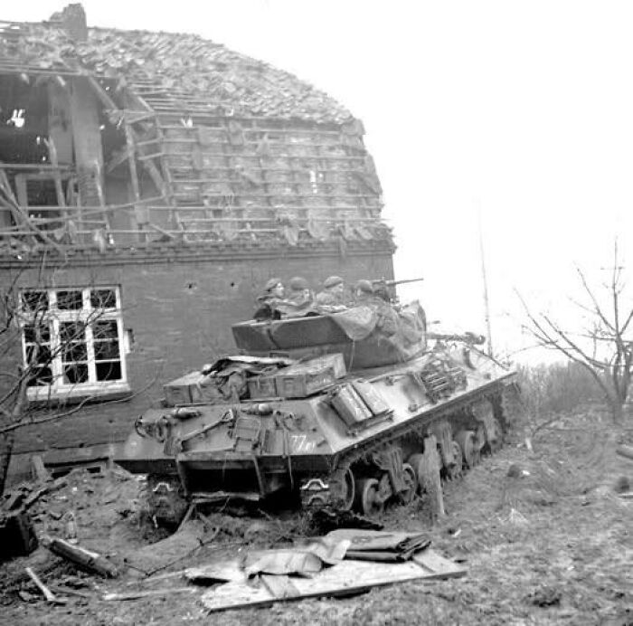 Historical image of a military tank with soldiers near a damaged building, evoking nostalgia.