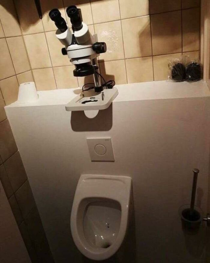 A microscope humorously positioned above a urinal, creating a funny random scene.