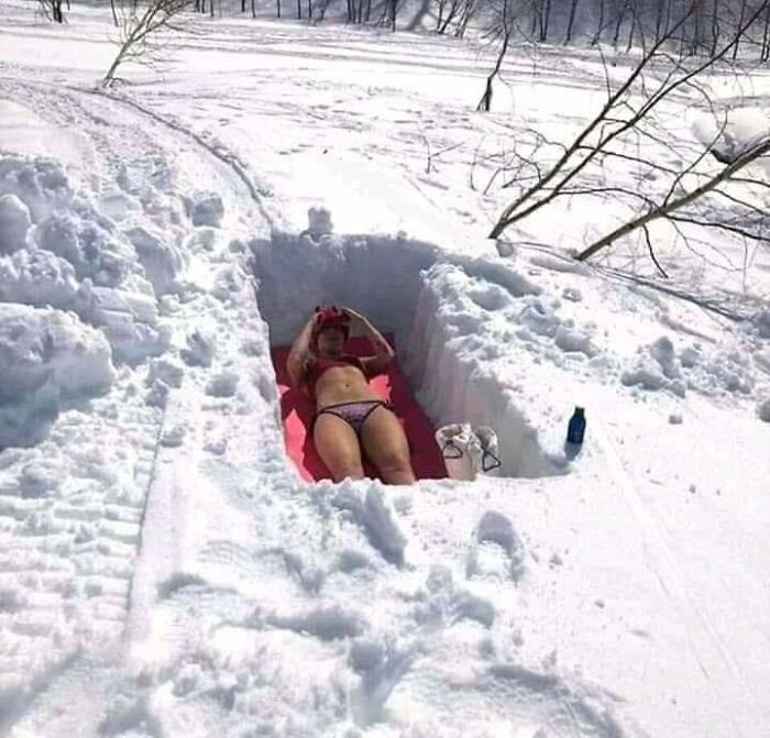 Person sunbathing in bikini on snow mat, humorous random photo.