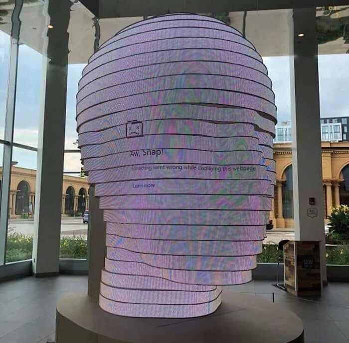 Sliced head sculpture displaying a browser error message, creating a randomly funny visual in the gallery space.