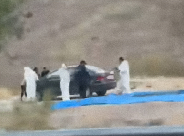 People surrounding a black car at a road. People surrounding a black car at a road.
