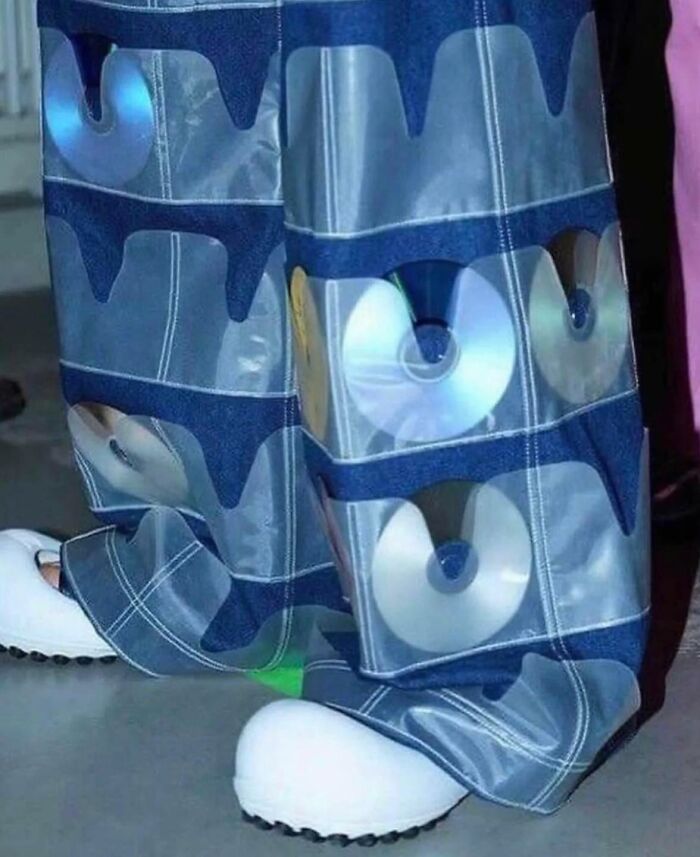 Jeans with CD pockets over white shoes, showcasing a humorous fashion statement.