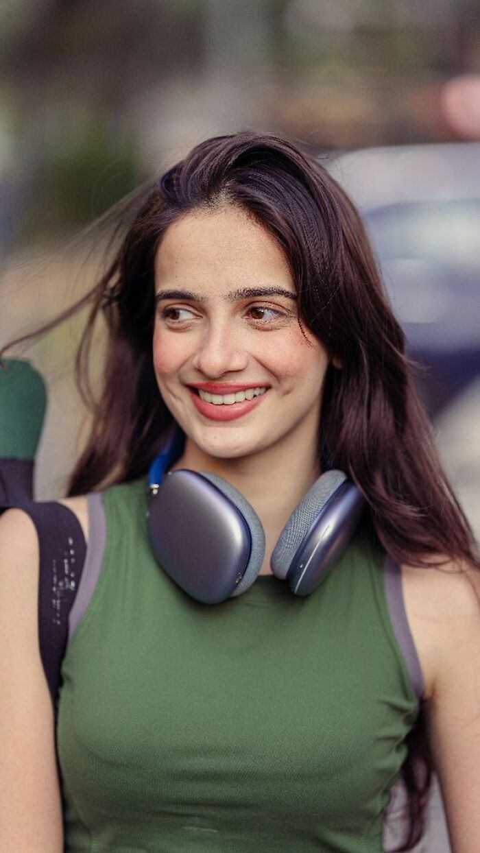 Smiling woman with headphones, portrait by Indian photographer capturing the beauty of strangers.