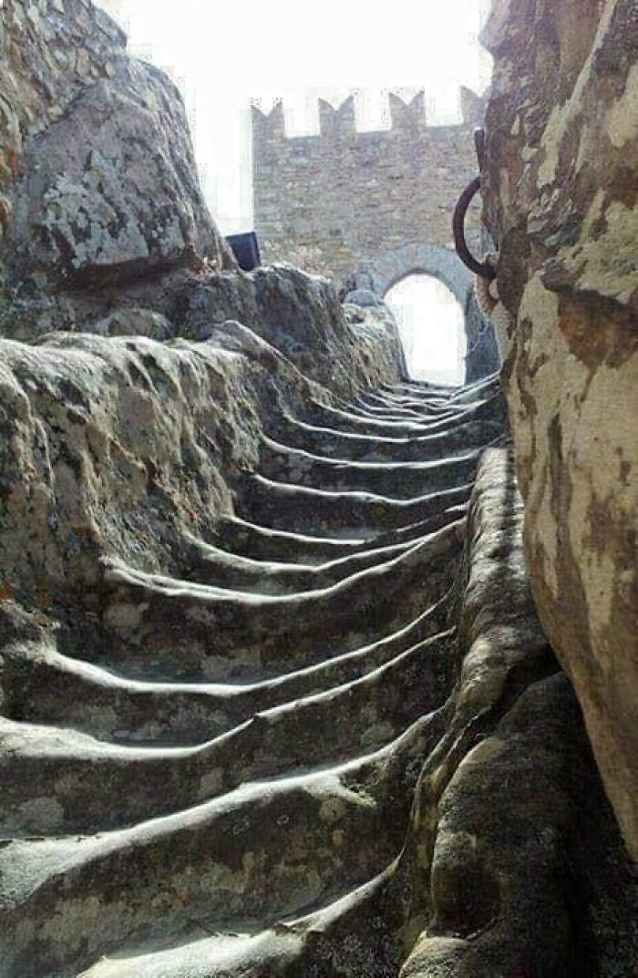 Stone stairs shaped by time and use, leading to a historic stone archway.
