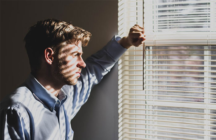 Man contemplating solutions for male loneliness, looking out a sunlit window.