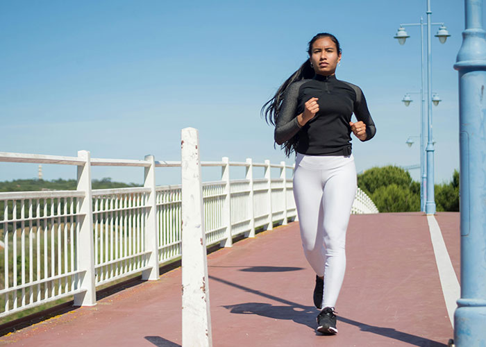 Woman running on a sunny day, enjoying fitness and exercise at the gym. Woman running on a sunny day, enjoying fitness and exercise at the gym.