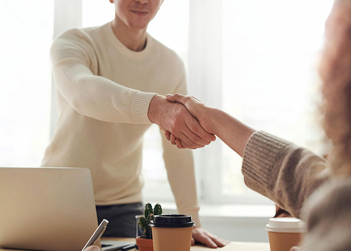 Two people shaking hands in an office, indicating a potentially toxic workplace interaction.