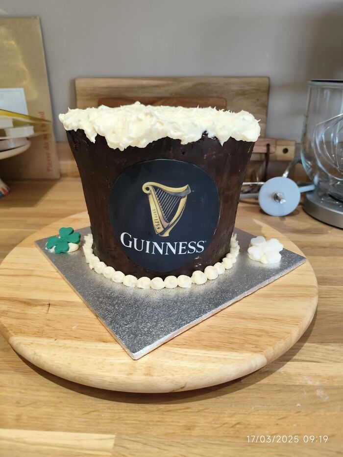 Guinness-themed cake on a wooden board, with white icing resembling beer foam, showcasing a funny baking fail.