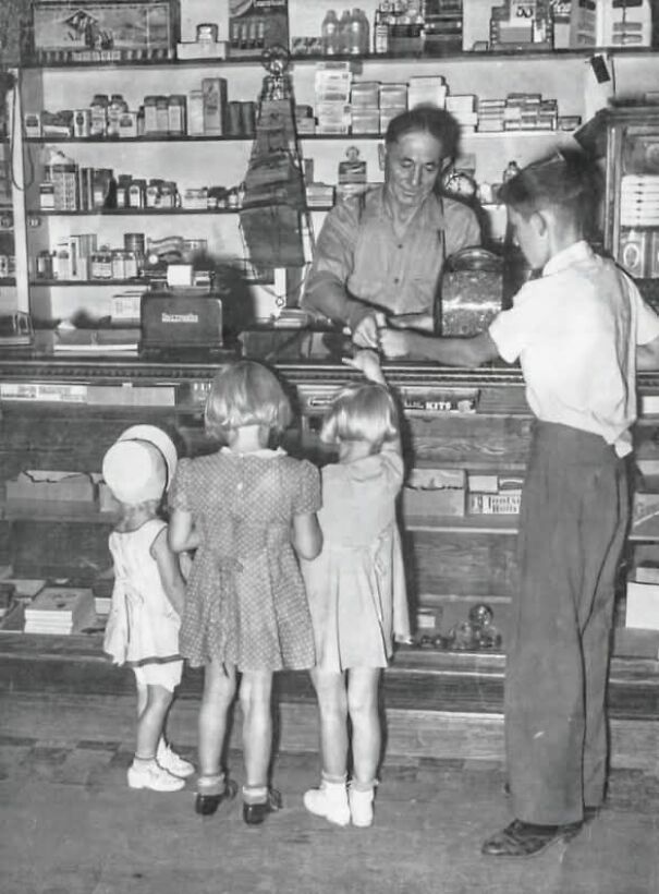Children at a vintage store counter interacting with the shopkeeper, showcasing an interesting historical perspective.