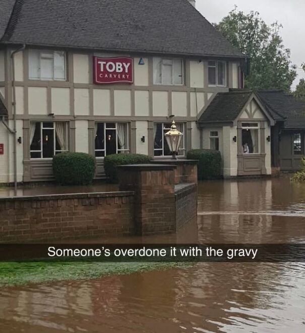 Pub surrounded by floodwater with humorous caption about gravy, showcasing Scots' humor.