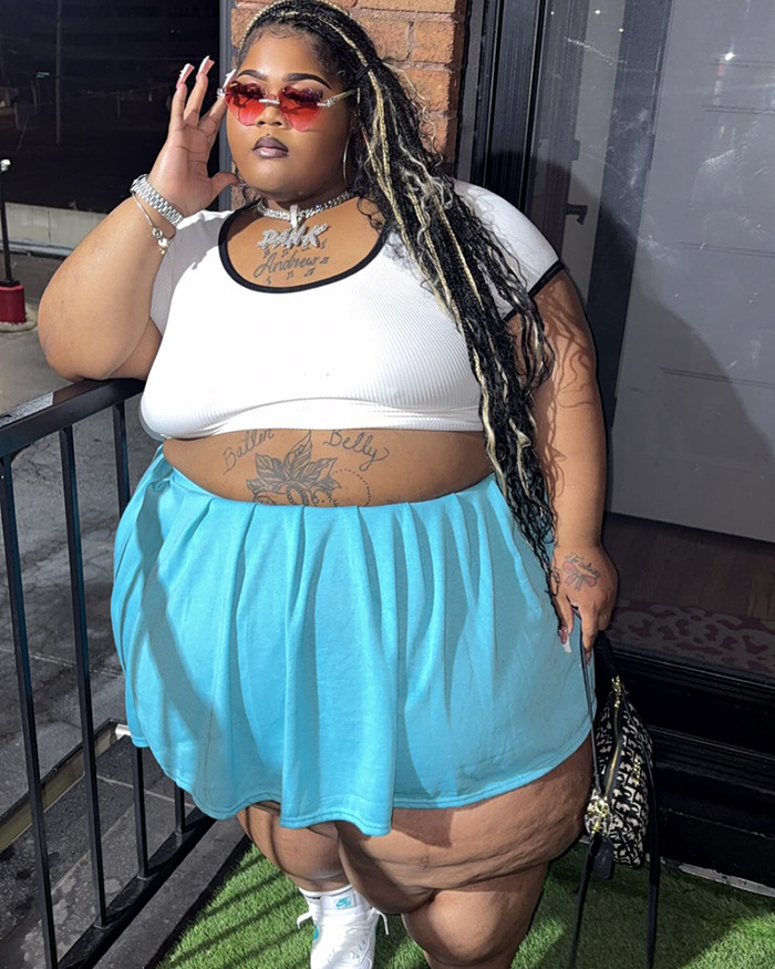 Plus-size rapper poses confidently in a stylish blue skirt and white top for a new photoshoot. Plus-size rapper poses confidently in a stylish blue skirt and white top for a new photoshoot.