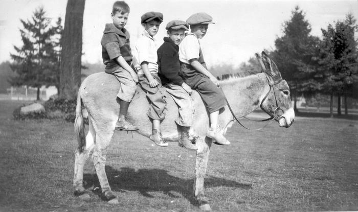Four children sitting on a donkey in a vintage black and white photo, illustrating how much the world has changed.