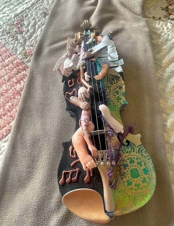 Strange violin-shaped object found while thrifting, decorated with eclectic patterns and sculpted arms.