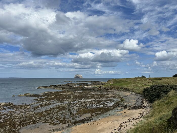 Coastal golf course with breathtaking views of the sea and dramatic clouds, attracting golfers worldwide.