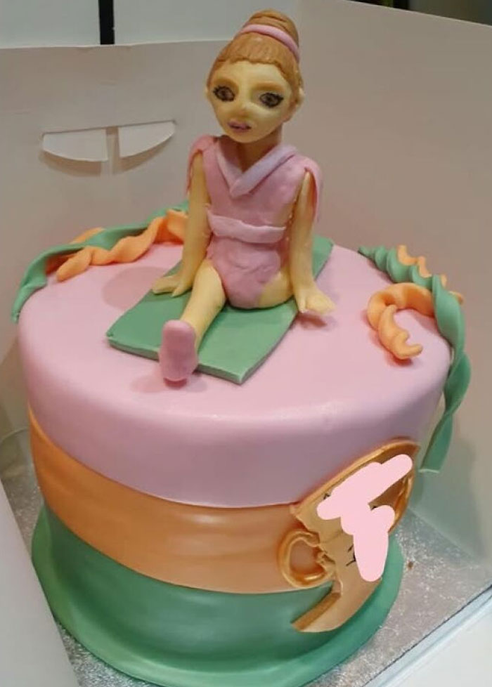 Cake showcasing a funny baking fail with a fondant figure in a pink outfit on a pastel-colored cake.