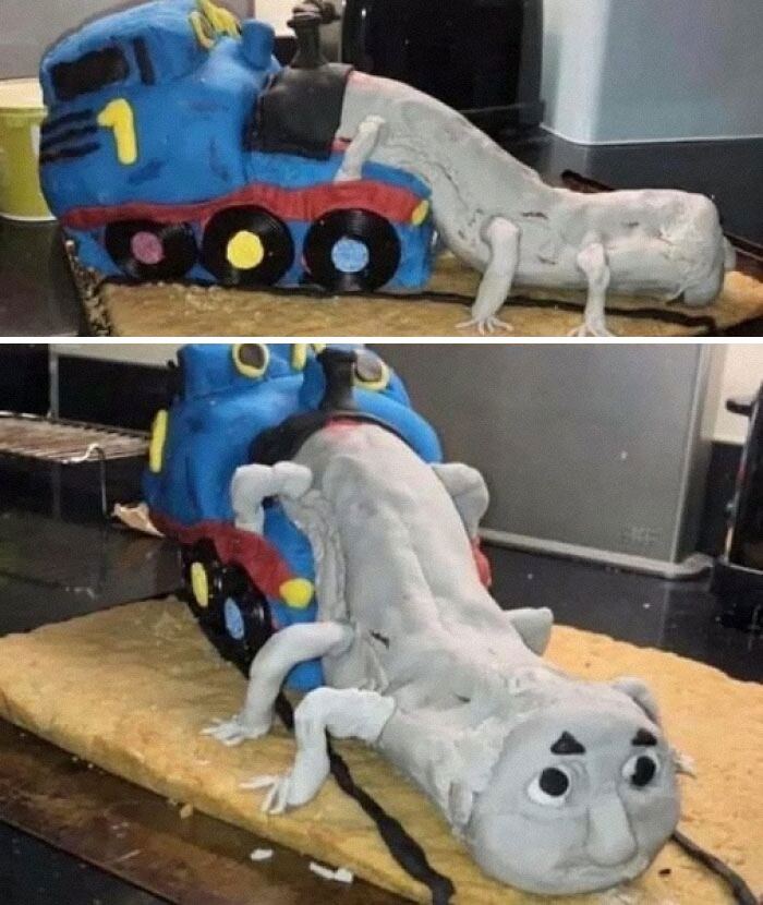 A funny baking fail cake shaped like a train and a worm on a kitchen counter.